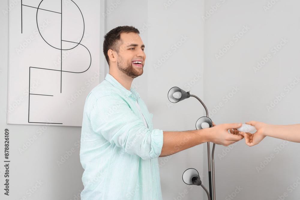 Young man taking light bulb for standard lamp from woman at home