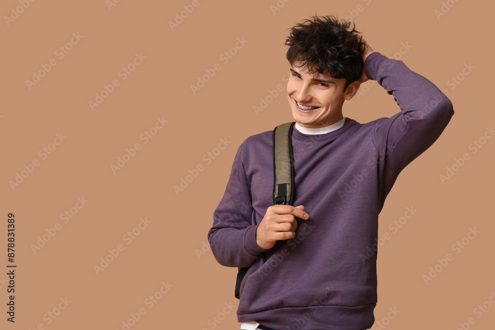 Handsome young man in stylish clothes with backpack on brown background