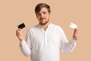 Wall Mural - Young man with credit cards on beige background