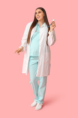 Poster - Beautiful young pregnant doctor with stethoscope on pink background