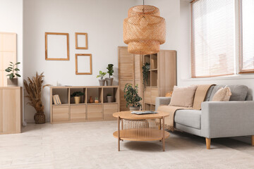Wall Mural - Stylish living room with folding screen, cozy sofa, lamp and shelving unit