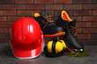 © New Africa - Pair of working boots, hard hat, protective goggles and earmuffs on grey surface