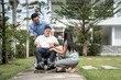 © Kawee - Asian attractive family walking with young son on wheelchair in garden.
