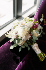 Wall Mural - An elegant wedding bouquet on a purple velvet seat and facing the window