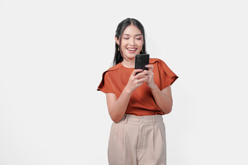 Wall Mural - Happy young Asian woman is smiling while holding a cell phone to text someone or open social media, isolated by white background.