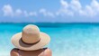 © Pual GotoMars - Woman in a straw hat relaxing on a tropical beach with clear blue waters and a sky filled with fluffy clouds.