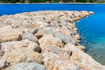 Wall Mural - Rocky pier with a body of water in the background.  The rocks are large and jagged leading to the sea, creating a rugged and natural landscape