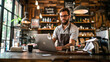 © EmmaStock - A man wearing a beard and apron is sitting at a desk with a laptop