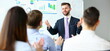 © H_Ko - Young handsome teacher man in suit with workgroup seminar board with chart coaching background. Lecturer for applicants retraining financial statistics management enterprise etiquette corporate spirit