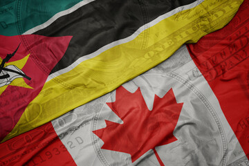 Wall Mural - waving colorful flag of mozambique and national flag of canada on the dollar money background. finance concept.