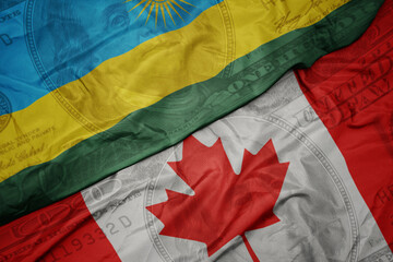 Wall Mural - waving colorful flag of rwanda and national flag of canada on the dollar money background. finance concept.