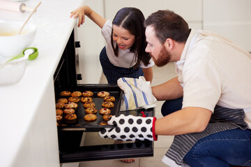 Sticker - Oven, girl and father with cookies for baking, preparation and checking on tray in home kitchen. Family, dad baker and happy kid for skills development, learning and observation of biscuits by stove