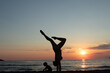 © Alessandro Grandini - Young mother practicing yoga pose on the beach at sunset with her son