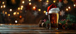 © sornram - Glass of beer wearing Santa hat on rustic wooden table with festive Christmas decorations and blurred lights in background.