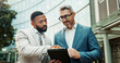 © SneakyPeakPoints/peopleimages.com - Business, men and outdoor with tablet in city for strategy on planning, teamwork and collaboration. Employees, communication and review or feedback with partnership, discussion as property developer