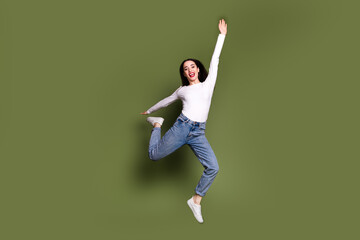 Poster - Full size photo of pretty young girl jump raise hand excited wear trendy white outfit isolated on khaki color background