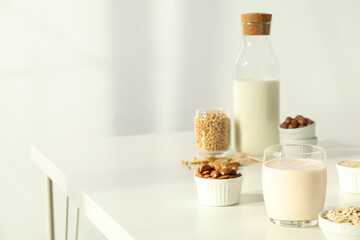 Wall Mural - Bottle and glass of alternative milk and herbal ingredients on light background, space for text