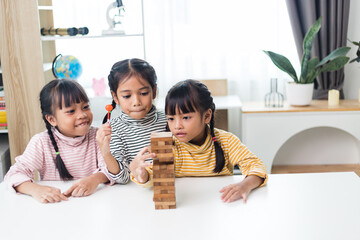 three sibling Asian girl playing wooden stacks at home