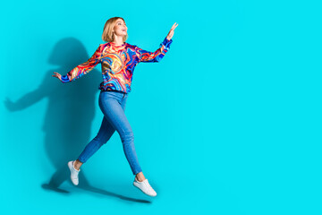 Poster - Full size photo of optimistic adorable girl dressed print shirt jeans look at discount empty space isolated on blue color background