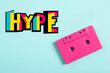 © New Africa - Hype word of bright letters and pink audio cassette on cyan background, top view