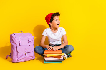 Wall Mural - Full body photo of cute little boy look empty space books backpack dressed stylish white clothes isolated on yellow color background