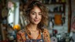 © svastix - A young woman with curly hair and a warm smile is standing in a colorful artistic workspace filled with various tools and decorations, embodying creativity and positivity.