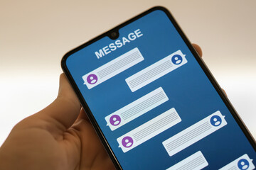 A close-up image of a hand holding a smartphone displaying a messaging app screen with blank conversation bubbles. Perfect for illustrating communication or technology themes.