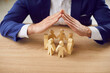 © Studio Romantic - Business employer executive manager protecting rights of employees. Man holding hands over group of small little wooden human doll figures on table. Metaphor for care, protection and safety at work