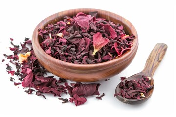 Canvas Print - Wooden spoon in bowl of fragrant Hibiscus tea on white background