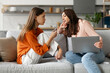 © Home-stock - Mother sitting on sofa with laptop spying on teen daughter using cellphone, mom and kid spending leisure time together on devices. Parental control and smartphone generation