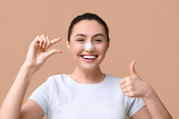 Poster - Happy young woman with bandaged nose showing thumb-up gesture on brown background. Plastic surgery concept