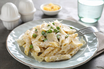 Delicious pasta with green peas, cheese and creamy sauce on grey table, closeup