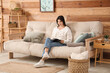 © Pixel-Shot - Young woman reading magazine and resting on comfortable sofa in living room