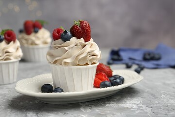 Wall Mural - Tasty cupcakes with different berries on light grey table, closeup