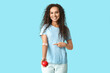 © Pixel-Shot - Young female African-American blood donor with heart pointing at applied medical patch on blue background