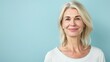 © kitipol - Half-body photo of a middle-aged woman smiling confidently, with a solid light blue background and ample copy space on the right side