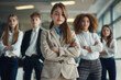 © Surachetsh - Young rookie girl and her team in suits, standing together in a modern office, with a bright environment and formal attire highlighting their potential as future leaders.