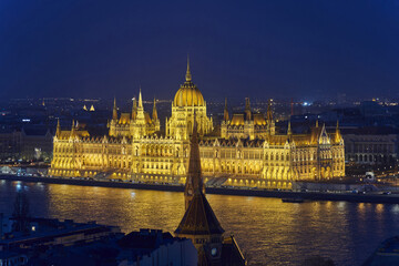 Budapest, Hungary - February 24, 2023: High angle and night view of Danube River and building of National Assembly with golden light
