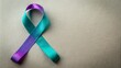 © Man888 - Teal and purple ribbon intertwined, symbolizing suicide prevention awareness, lies on a simple background with ample copy space available.