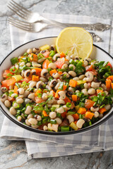 Wall Mural - Fasolia mavromatika or black-eyed pea salad with carrot, leek, tomato and herbs closeup on the plate on the table. Vertical