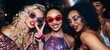 © Georgii - Three stylish women at a party wearing fashionable outfits and sunglasses