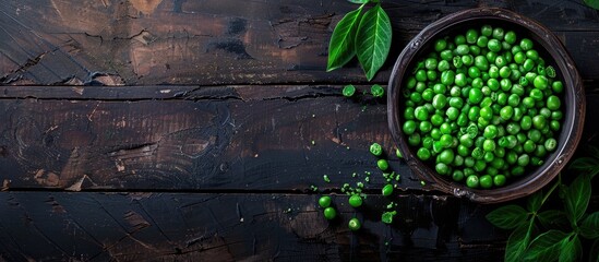 Poster - Top view of fresh organic raw green peas in a bowl with pea plants leaves on a dark wooden table background, ideal for healthy eating, vegan and vegetarian diets, with copy space image.