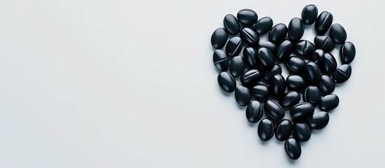 Poster - Medical black pills forming a heart with copy space image on white background, representing a medicine concept to cure pain and promote health.