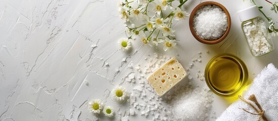 Poster - Wellness environment with sea salt, soap, towel, olive oil, and flowers on a white textured backdrop with room for a copy space image in a flat lay style.