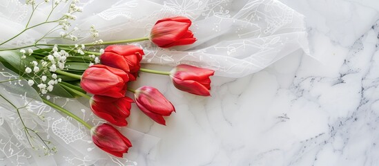 Poster - Top view of a red tulip bouquet with lace on a white table, providing copy space image.