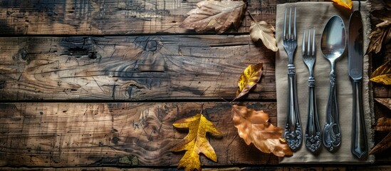 Aufkleber - Rustic autumn-themed table setting for Thanksgiving with cutlery, leaves on wooden table. Top view with ample copy space image for text.