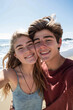 © BetterPhoto - Smiling young couple taking a selfie on a sunny beach. Happy and relaxed vacation moments by the sea.