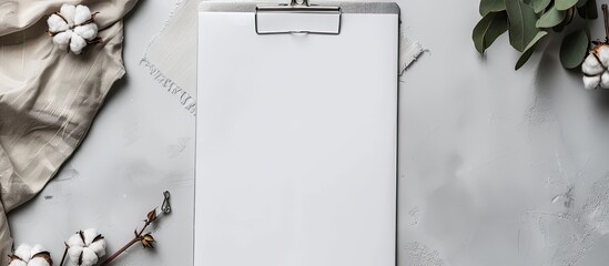 Poster - Top view of a blank white paper on a gray background with a folder, a metal clothespin, and a cotton branch, providing copy space.