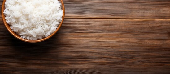 Poster - Top view image of a bowl of cooked rice on a wooden background with ample copy space for text or graphics.