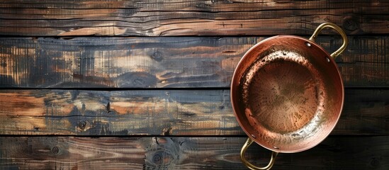Poster - Top-down view of a copper pot on a dark wooden table with copy space image.
